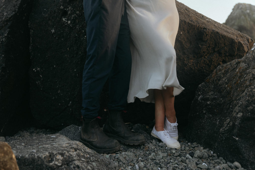 Couple standing against a rock formation holding hands on the Oregon Coast 