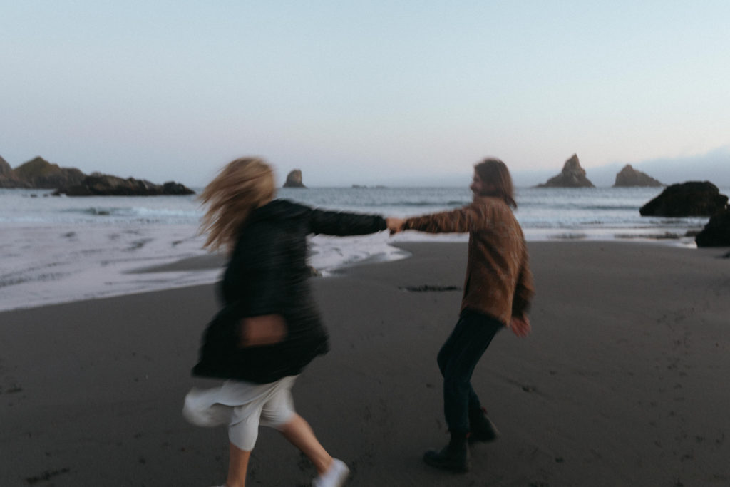 Couple spinning eachother joyfully around in circles on the Oregon Coast