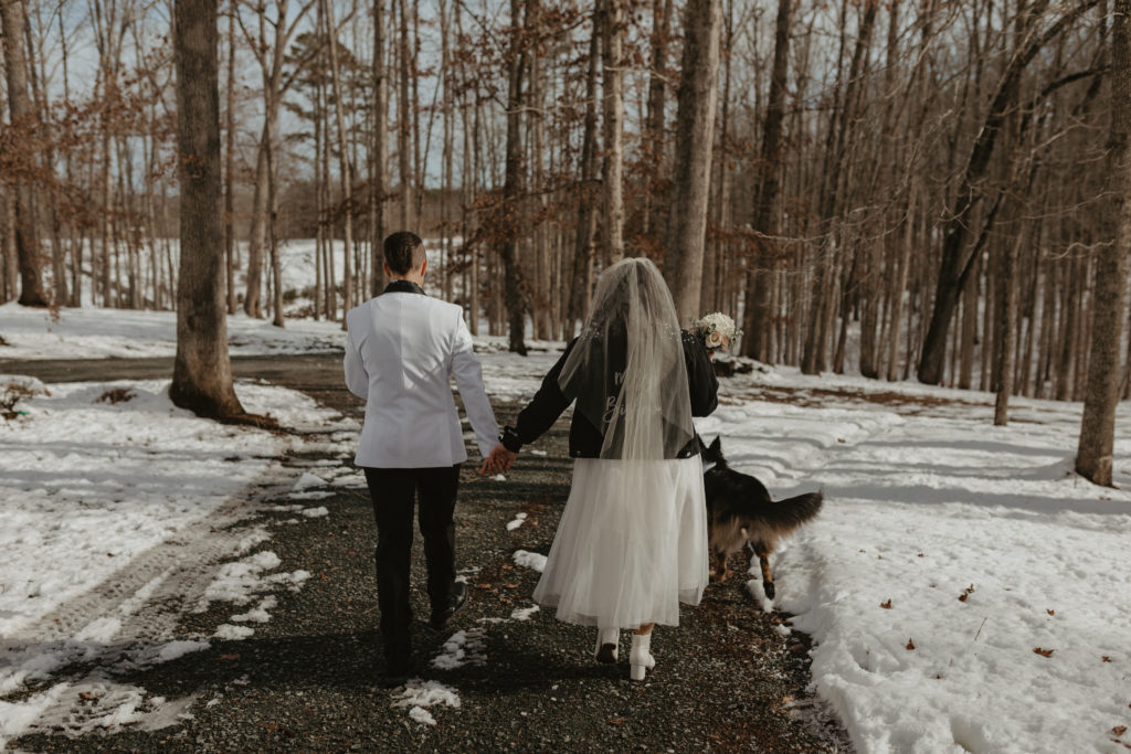 Couple walking in the snow laughing together after their winter elopement in the mountains 