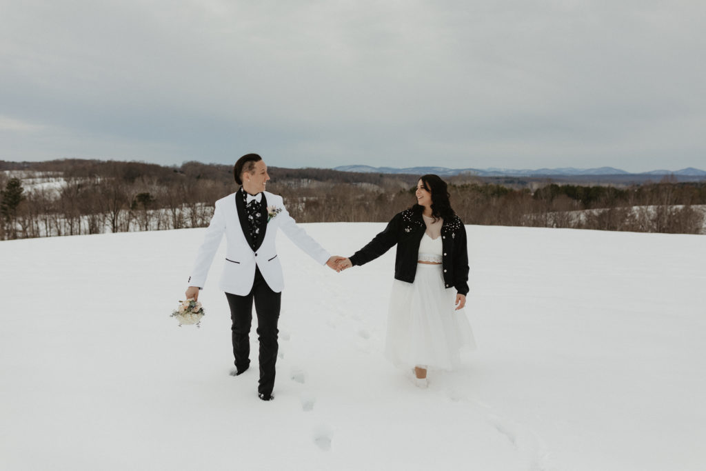 Couple standing in the snow laughing together after their winter elopement in the mountains 