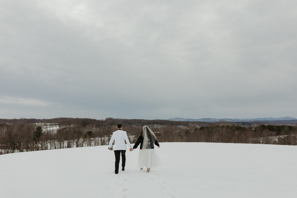 Couple standing in the snow holding hands together after their winter elopement in the mountains 